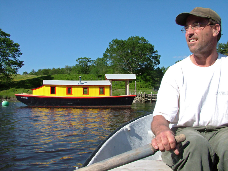Maynard Haslett, of Washington, rows a dingy out to his 30-foot riverboat, "Shanty," anchored in the Passagassawakeag River in Belfast. (Photo by Ethan Andrews)