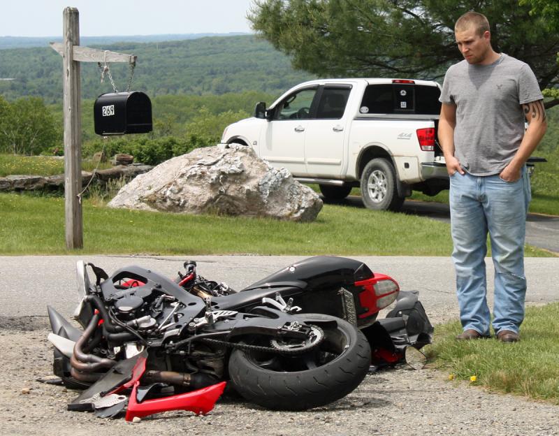Vernon Kvorjak of Owls Head and his broken Suzuki motorcycle on Mill Street in Rockport late Monday morning. (Photo by Holly S. Edwards)