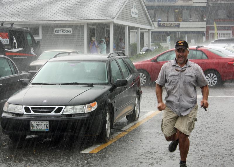 Camden Harbormaster Steve Pixley sprints back through the downpour after rolling up his car windows. (Photo by Holly S. Edwards)