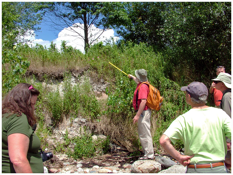 Ron Huber, center, points to an eroding bank at the edge of the GAC property that he hopes the company will stabilize to prevent the erosion of potentially polluted soil into the bay. (Photo by Ethan Andrews)