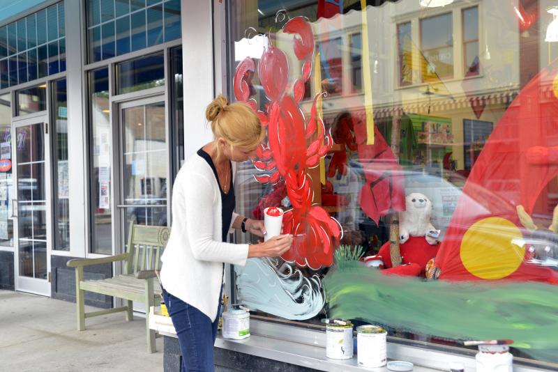 Marjanne Raddmaker of Owls Head paints the windows of Planet Toys for the Lobster Festival that begins Wednesday. (Photo by Ron Hawkes)