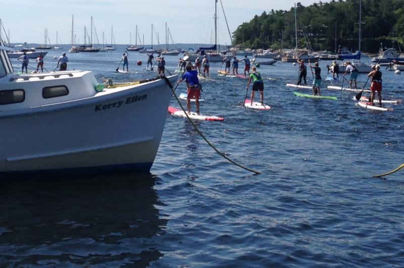 The Lobster SUP Cup racers barrel past a Rockport Harbor lobster boat. (Photo by Lynda Clancy)