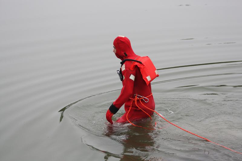 Thomaston firefighter Colby Miles wades into the Weskeag River. (Photo by Holly S. Edwards)