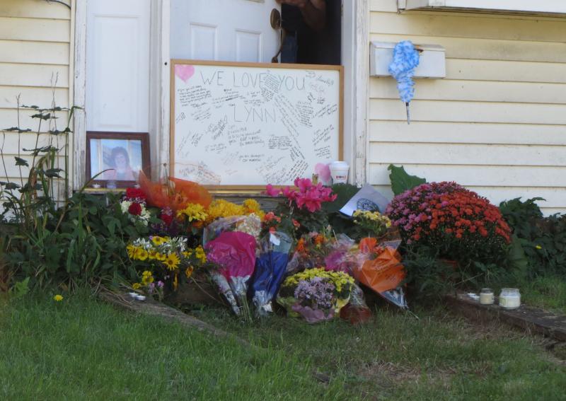 A whiteboard is full of messages about Lynn Marie (Day) Arsenault at the site of the shooting, at her home on Waldo Avenue, along with flowers and a picture. (Photo by Erica Thoms)