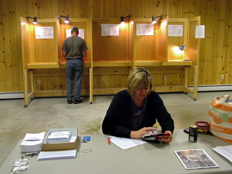 Searsmont Selectman Christopher Staples, background, fills out his ballot on Sept. 17, while Election Moderator and Warden Tammy Roberts passes a quiet moment at the polls. Searsmont was one of two towns to hold votes on withdrawing from Regional School Unit 20 on the same day as an eight-town vote on the district’s budget. (Photo by Ethan Andrews)