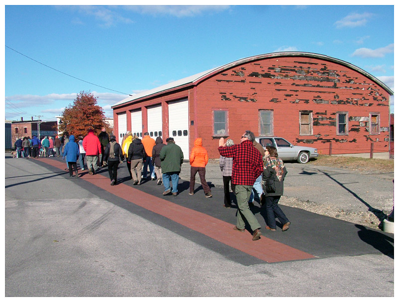 Harbor Walk grand opening attendants pass in front of one of several commercial properties that account for an inland detour on the mostly-waterfront path. (Photo by Ethan Andrews) Harbor Walk grand opening attendants pass in front of one of several commercial properties that account for an inland detour on the mostly-waterfront path. (Photo by Ethan Andrews)
