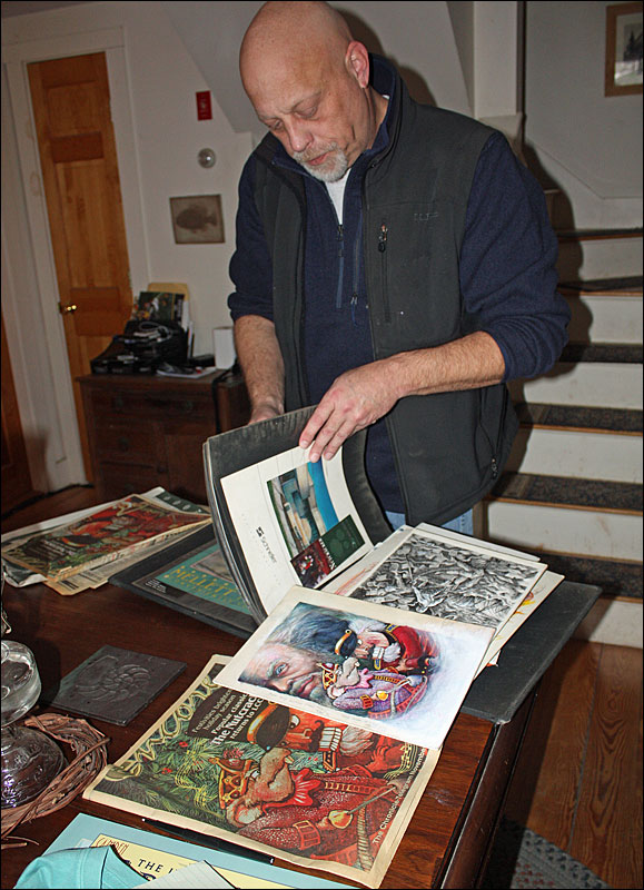 Ben McGinnis thumbs through his illustration portfolio in the kitchen of his home in Hope. (Photo by Holly S. Edwards)