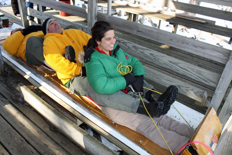Bangor Daily News reporter Abigail Curtis is joined by veteran toboggan racers Ben Hazen and Jim Tyler Friday for a ride down the chute during Media Day. (Photo by Holly S. Edwards)