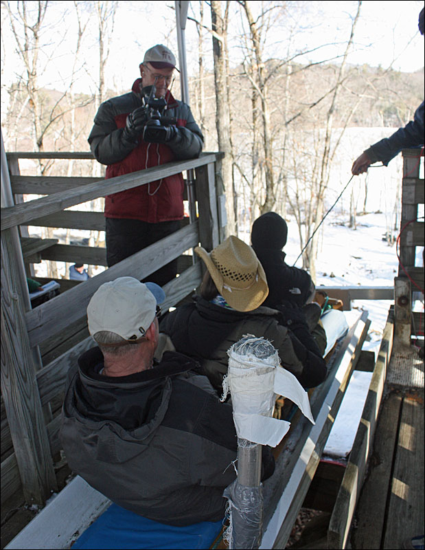 The seated WABI 5 crew talk to Charlie Crockett of Maine TV85 before they head down the chute with veteran toboggan racer and U. S. National Toboggan Championships committee member Tom Cox in the back of the sled. (Photo by Holly S. Edwards)