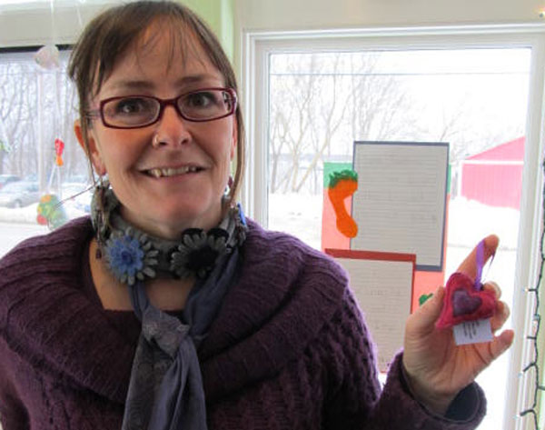Teisha Hufnagel Jones, education outreach and membership coordinator of the Good Tern, displays a felted heart ornament made by Kate Chandler of Orange Iron Studios, also a member-owner. (Photo by Kay Stephens)
