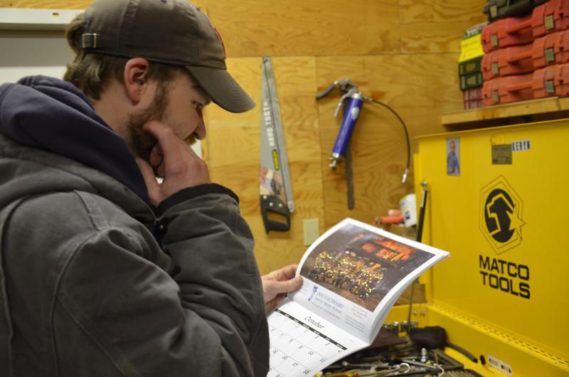 Pit Master Travis Brown casts a critical eye on the Lincolnville Fire Department’s 2014 calendar. (Photo by Lynda Clancy)