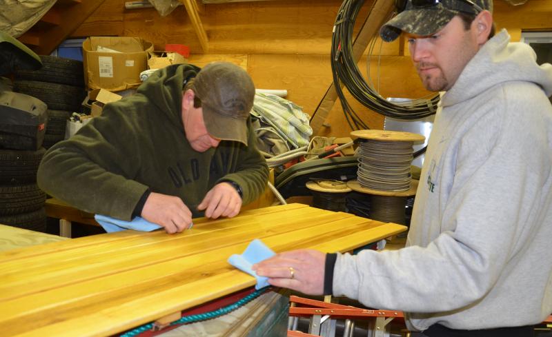 Teammates Glen Wiley, of Lincolnville, and Matt Haynes, of Rockport, carefully wax and buff the bottom of their toboggan, prepping for Saturday’s first run at the Toboggan Nationals. (Photo by Lynda Clancy)