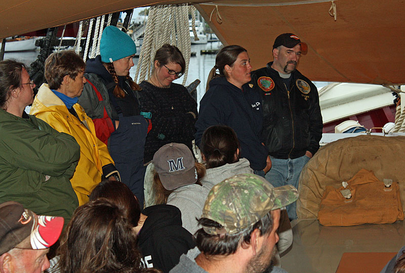 Crew of schooner Mary Day and Appleton Village School parents and students keep dry under the canopy Tuesday night. (Photo by Holly S. Edwards)