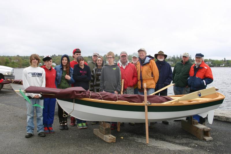 Searsport District High School sophomores stand with lead instructor Greg Rossel, far right, and other volunteers behind one of the two dinghies they created. (Photo by Erica Thoms)