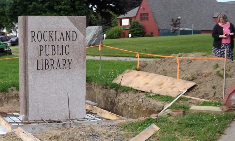 Rockland Librarian Amy Levine watched the proceedings as the Rockland Public Library's new granite sign is installed at the corner of Beech and Union streets Tuesday, June 16. (Photo by TimO)