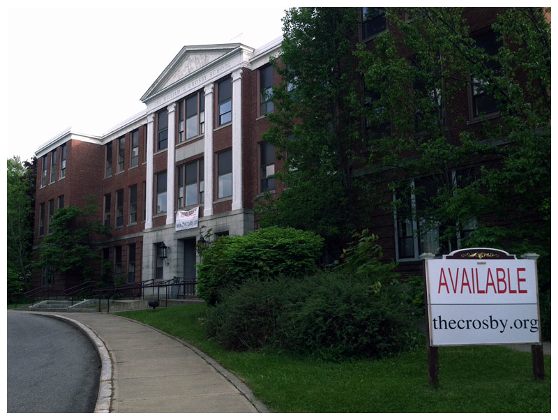 Signs posted outside the former high school have been the source of some confusion in the community since they went up six months ago. The bold “available” suggests the building is for sale, but a message on the website disclaimed any commercial intent. (Photo by Ethan Andrews)