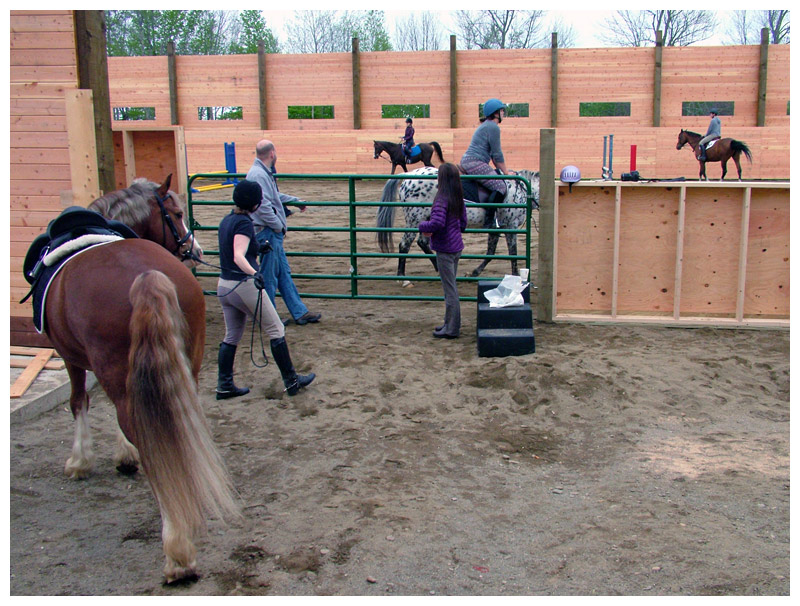 Riders circle the arena behind the barn. The 80-by-200-foot riding area will eventually be covered. (Photo by Ethan Andrews)