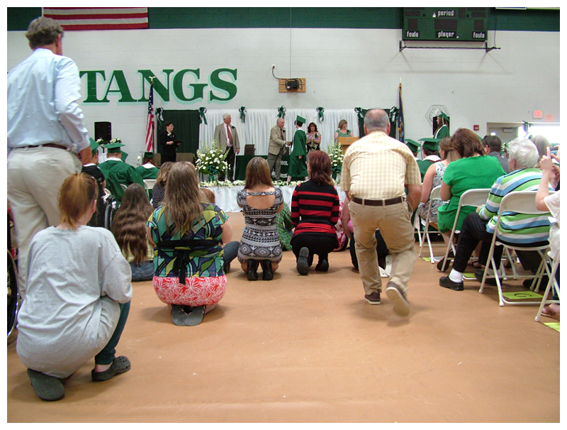 Parents crowd into the center aisle to snap pictures of graduates receiving their diplomas.