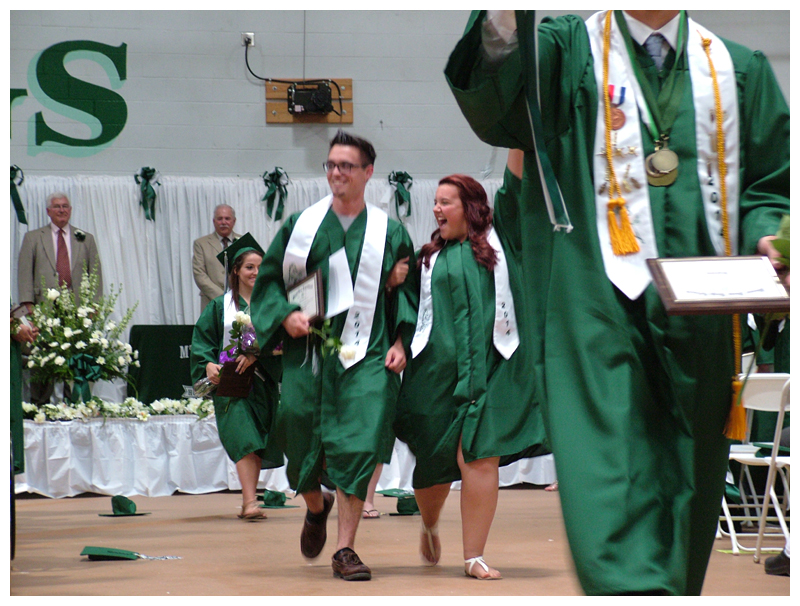 Graduates flash smiles to family and friends as they leave with their diplomas.