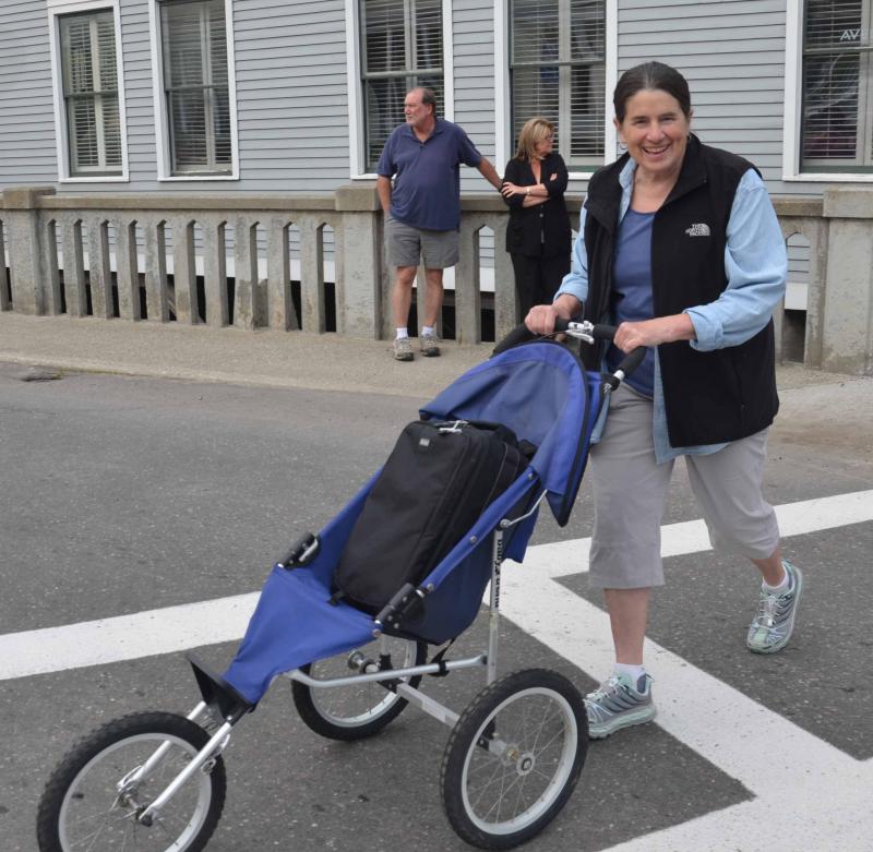 Photographer Marti Stone wheels her precious cargo — her cameras — across the street before the march. (Photo by Lynda Clancy)