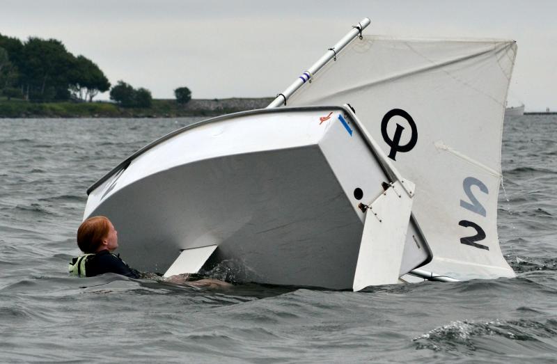 An optimist prams racer capsized during the July 27 race and is seen trying to turn the boat right-side-up. (Photo by George Harvey)