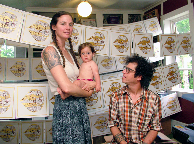 Amy Moon, Dan Beckman and their daughter Agnes at home in Belfast. The couple has been making music together for over a decade, most recently under the name Village of Spaces. Here, hand-silkscreened LP covers dry between coats in the room where much of the band’s new album, “Welcome In,” was recorded. (Photo by Ethan Andrews)