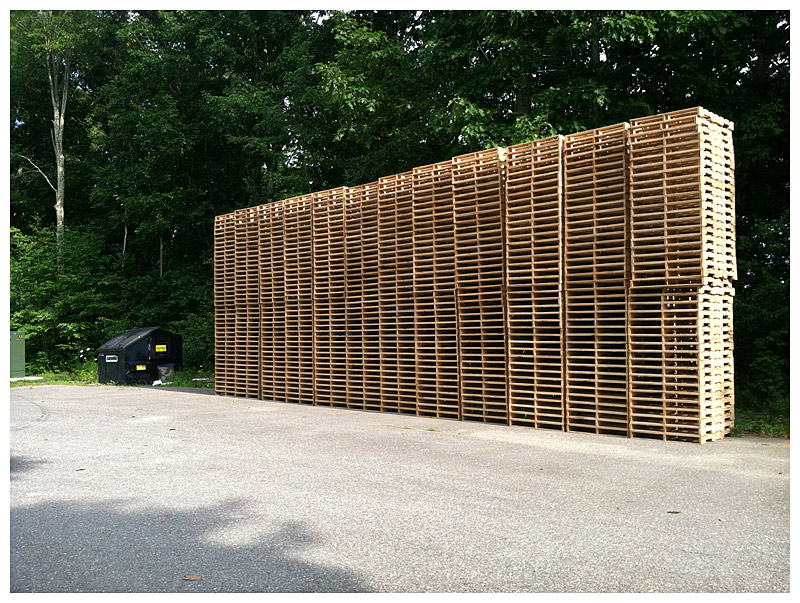 Stacks of pallets stand at the edge of the parking lot at the former Coastal Farms and Foods facility. This week, the new owner of the company’s blueberry processing equipment resumed operations in time for the start of the Canadian blueberry harvest. (Photo by Ethan Andrews)