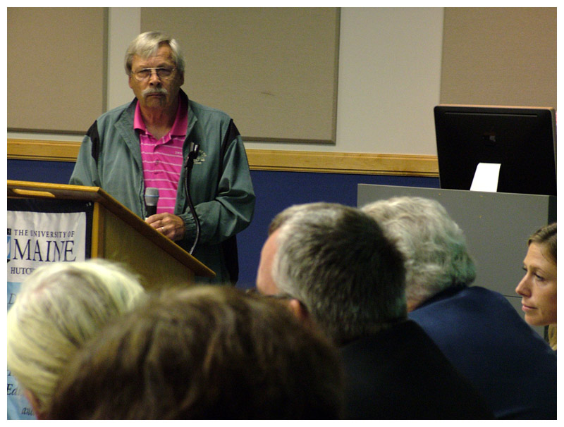 Regional School Unit 20 board member Stephen Hopkins of Belmont, standing at podium, listens to responses from the panel of statehouse candidates. (Photo by Ethan Andrews)