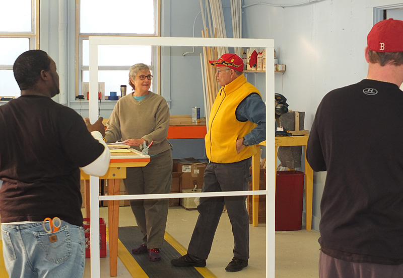 Workers add foam around the window insert and check for quality control before signing off on a finished product.