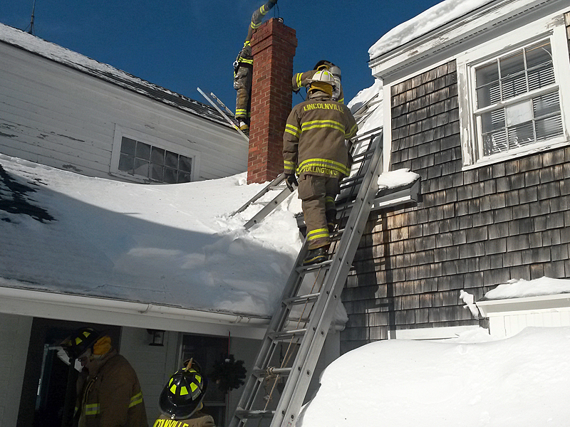 Due to the arrangement of the Yarnell’s roof lines, and the chimney, an attic ladder had to be used to allow Lincolnville firefighters to get above the chimney opening to drop a chain down and dislodge burning creosote inside. (Courtesy Lincolnville Fire Department)
