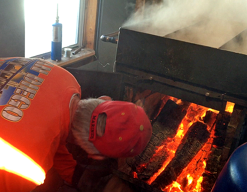 Skip Pound fills the fire box under the maple syrup extractor Wednesday. (Photo by Holly S. Edwards)