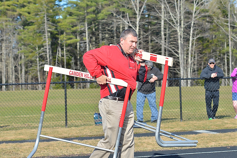 Camden Hills Athletic Director Steve Alex helps clear the hurdles off the track as they get ready for a different meet. (Photo by Ron Hawkes)