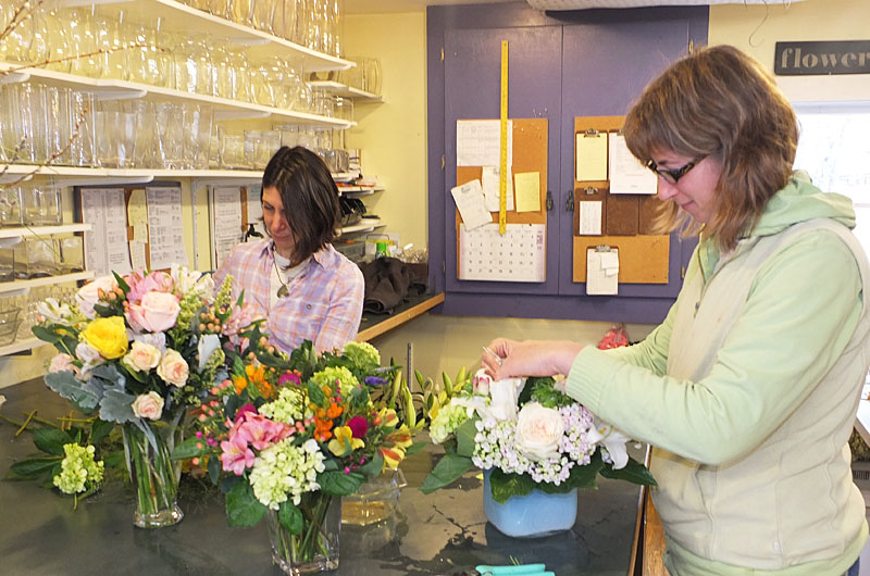 Melanie Flach and Alyssa Bregman work on flowers for a wedding.