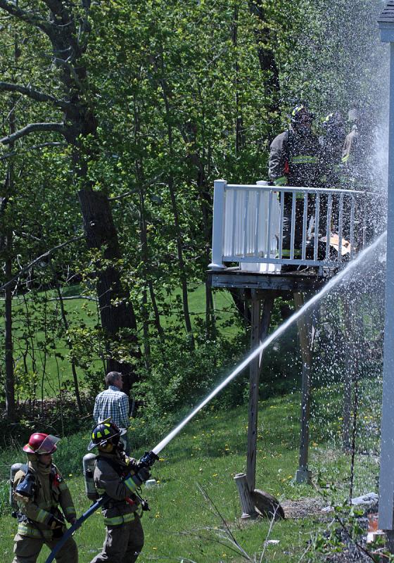 Firefighters work on the fire at the back of the residence, where and outside wall and the kitchen inside were most damaged Thursday afternoon. (Photo by Holly S. Edwards)