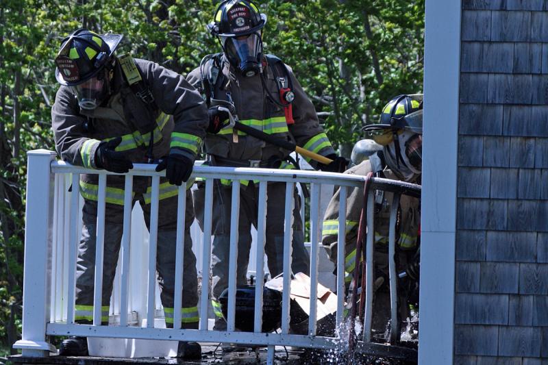 Firefighters work on fire at the back of the home at 40 John St. Thursday afternoon. (Photo by Holly S. Edwards)