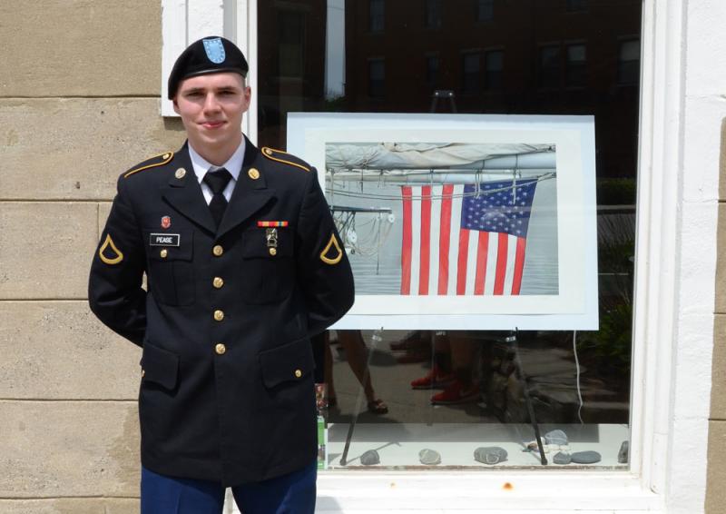 Caleb Pease, in front of a Peter Ralston photo in the gallery window at Rockport corner. (Photo by Lynda Clancy)