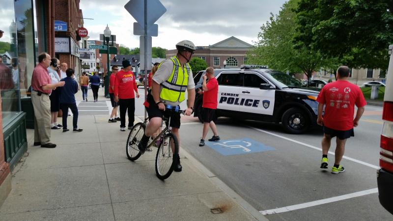 Justin Hills is on his bicycle and Lt. Mike Geary is driving a Camden Police cruiser, to escort the runners along Route 1. Photo by Sarah Shepherd