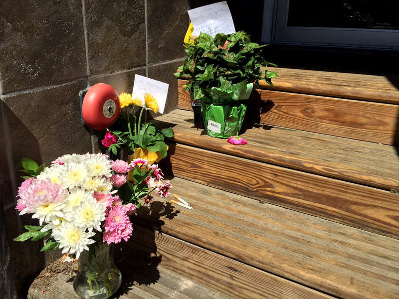 David Conary could often be found recently sitting in this vestibule, next to French and Brawn Market Place on Elm Street. He will never sit there again, and this week flowers have been left in his place. Conary was 55 when he was found deceased June 15 in a stand of trees between the Knox Mill and Rite Aid parking lots. (Photo by Holly S. Edwards)