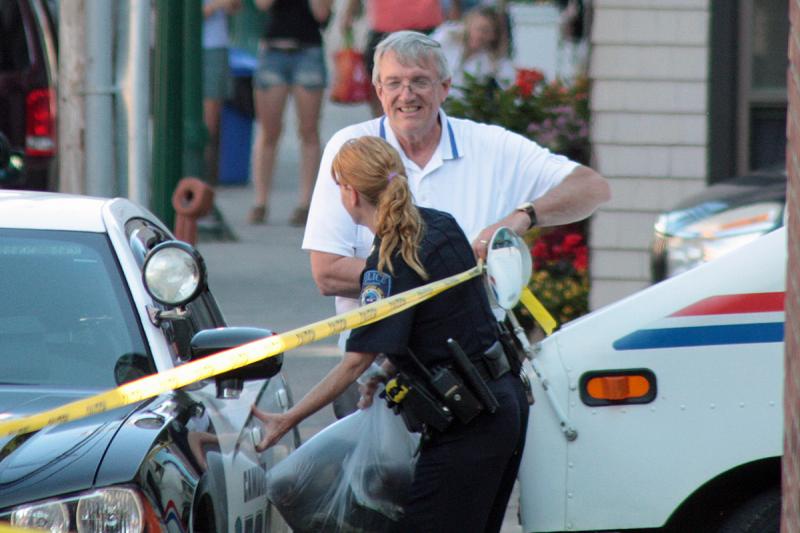 Camden Postmaster Stephan P. Dalessandro looks happy while collecting the police tape and talking to Camden Police Officer Brook Hartshorn following the successful removal of the backpack from behind the post office building Friday afternoon. (Photo by Holly S. Edwards)