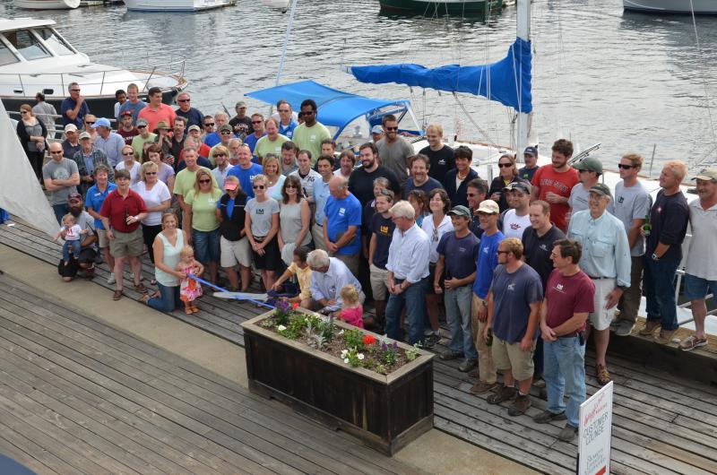 The crews of Wayfarer Marine and Lyman-Morse assemble behind the Lymans as they cut the symbolic ribbon of a new venture. (Photo by Lynda Clancy)