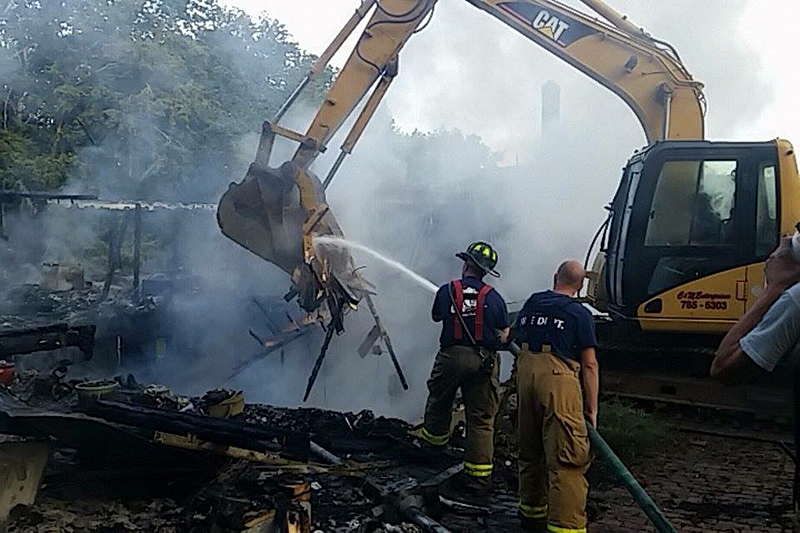 An excavator digs through the rubble of Chesley Farrell’s home in Union and firefighters hose it off, to extinguish the remaining hot spots. (Courtesy photo)