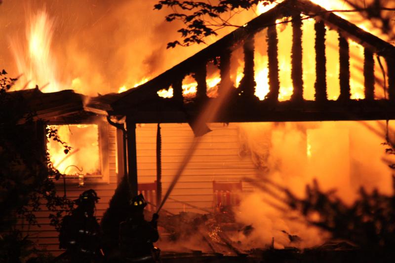 Firefighters spray water on what had been the front entrance to the home. (Photo by Holly S. Edwards)