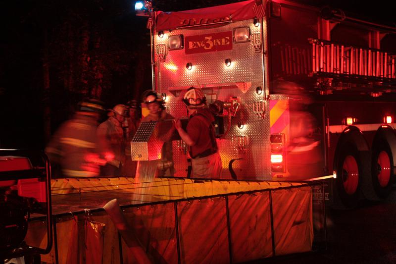 A portable water tank was set up on Payson Road, at the top of the driveway, to shuttle water in from a nearby pond That water was pumped through a fire engine to another engine down the driveway, close to the fire scene. (Photo by Holly S. Edwards)