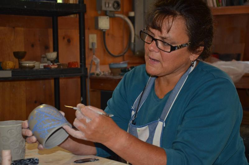 Avery Larned, who teaches pottery and ceramic arts at Hope Clay Studio, at the Hope Spinnery, carefully etches her final design in a cup. (Photo by Lynda Clancy)