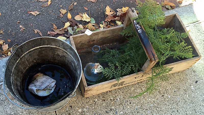 The burning napkin and melted plastic greenery was dropped into the bucket on the left to douse them with water, and the wood basket handle also needed to be extinguished.