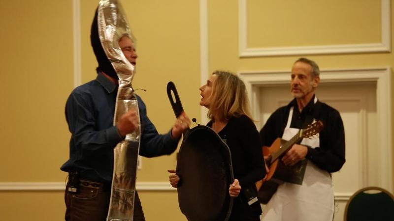 n The Afterhours Kitchen Cabaret smoking hot lyricist, guitarist and campaign volunteer John Burstein accompanies Lucinda Zeising, playing the part of a very unordinary kitchen pan. Zeising sang a duet with a Silver Spoon, Des Fitzgerald, about making flambés and crepe suzettes at night in the kitchen. Burstein‘s original musical production was the highlight of the fundraising kickoff party held at the Samoset Resort to expand the organization’s kitchen and produce more meals for seniors and people with special needs in Knox County.