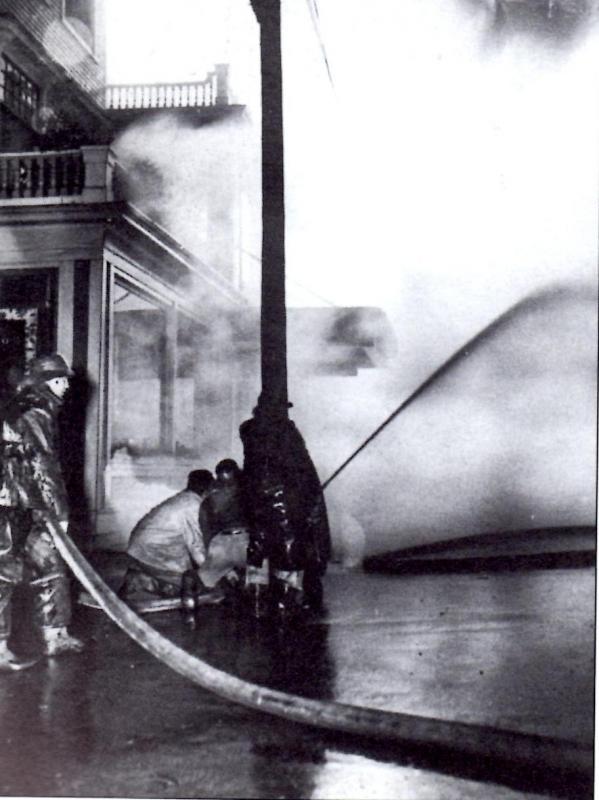 Firefighters stand below the porch of the Rockland Hotel as the Studley Furniture Co. fire spread. (Photo from “Around Rockland: Images of America. Copyright 1996.)