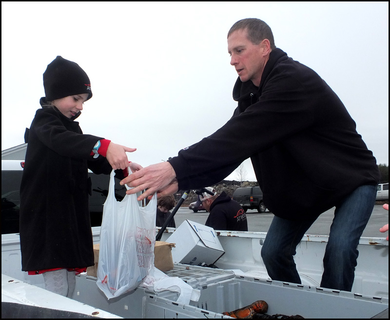 Noah’s daughter Nadia hold a bag as Noah puts lobsters in it.