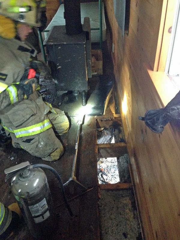 Lincolnville fiefighter AJ Weed works to remove the floor boards and expose the smoldering fire, which was drenched with water to put it out. (Photo courtesy Lincolnville Fire Department)