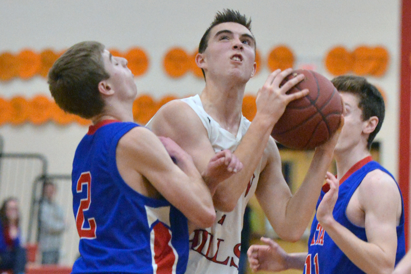 Camden Hills Noah Heidorn, center, struggles to get the shot off as he is fouled on the play by Mt. Ararat’s Cole Guerin, left, as teammate Eric Segars looks on. (Photo by Ron Hawkes)